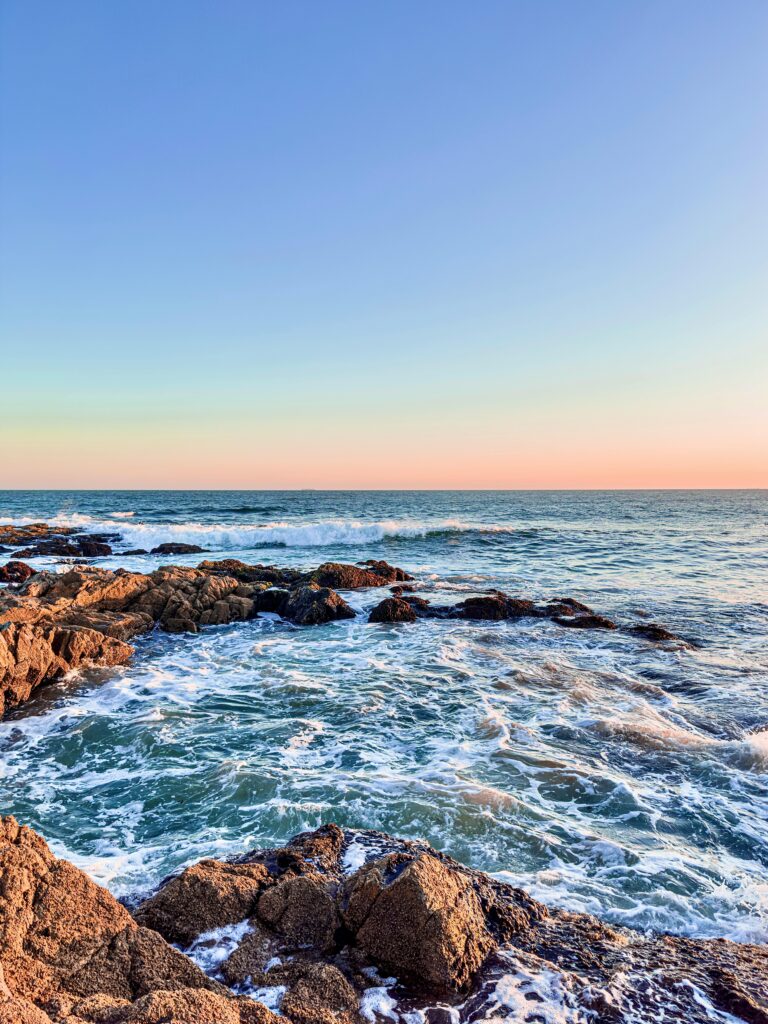 A serene sunset view of rocky cliffs and waves in Punta del Este, Uruguay.